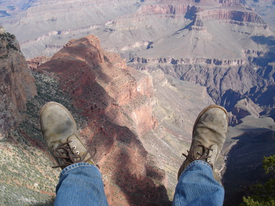 Legs and feet hanging over the edge of the Grand Canyon.